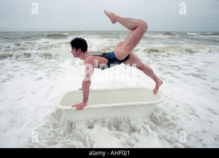 Young man performing gymnastic dance on a bathtub in the ocean Stock Photo