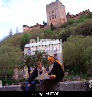 Women travellers looking at a map with a view of the Alhambra Palace in the background in Granada Andalusia Southern Spain  KATHY DEWITT Stock Photo