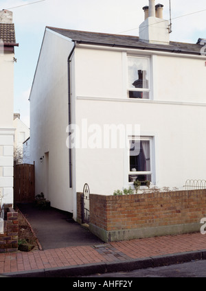 Well-painted white terraced cottage with low brick wall at the perimeter of front garden Stock Photo
