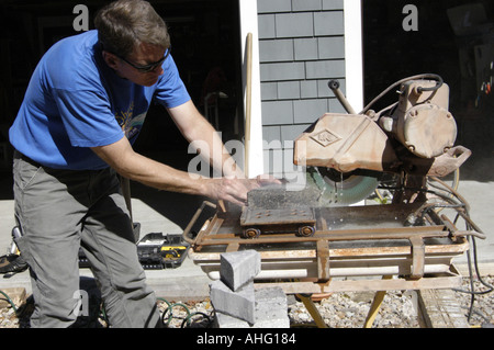 Worker using concrete cutting saw to cut pavers Stock Photo