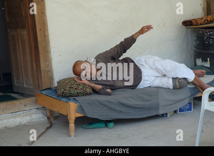 Man resting on bed on porch in rural village of Bezirgan in Southern Turkey. Stock Photo