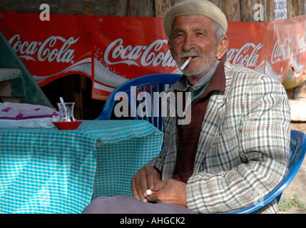 Portrait of elderly man smoking and drinking tea with  at cafe bar in Southern Turkish village. Stock Photo