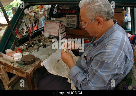 Man fixing and repairing watches from the back of his car in Kalkan a Southern Turkish town. Stock Photo