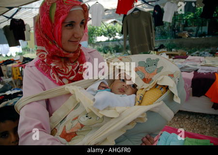 Mother with young baby in a basket at the market in Kalkan in Southern Turkey. Stock Photo