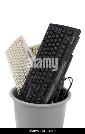 Keyboards piled into grey bin against white background Stock Photo