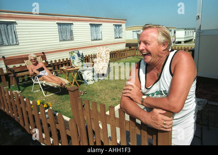 Senior couple relaxing in the sun outside their static caravan at Trecco Bay Porthcawl South Wales UK Stock Photo