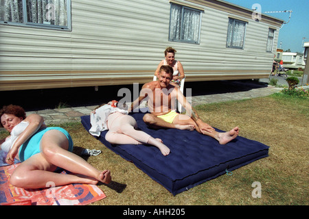 Family group relaxing in the sun outside their static caravan at Trecco Bay Porthcawl South Wales UK Stock Photo