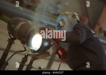 Welder working on a pipe for the oil industry in Milford Haven Pembrokeshire West Wales UK Stock Photo