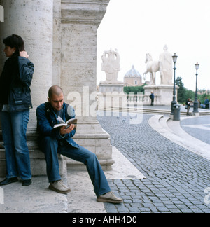 A man reading a book outside the Capitoline Museum in the Piazza del Campidoglio, Rome Italy  KATHY DEWITT Stock Photo