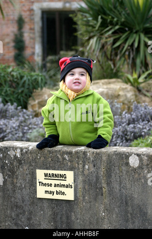 A small boy next to a sign which reads These Animals Bite Stock Photo