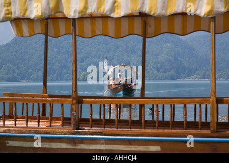 Lake Bled in summer with traditional wooden pletnja rowing boat ferrying tourists from island Bled Slovenia Stock Photo