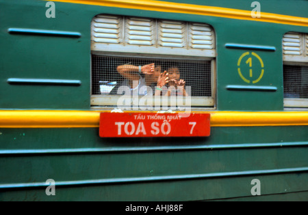 Children peering out of train carriage Vietnam Stock Photo