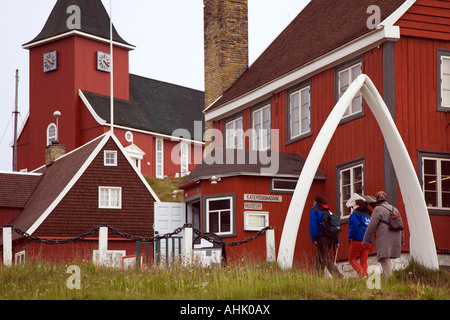 People walk through traditional whale jawbone arch entrance to local museum and Church at Sisimiut on west coast of Greenland