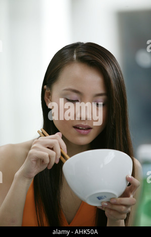 Asian woman eating using chopsticks Stock Photo