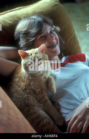 Teen wearing braces comforted by her cat Stock Photo