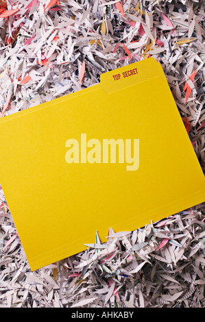 Yellow file folder top secret on pile of shredded paper Stock Photo