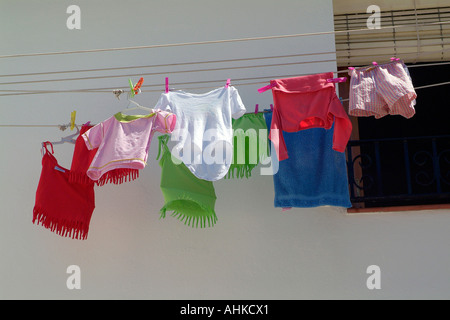 A striking and graphic humourous image of colourful childrens clothing hanging from a washing line in a small spanish village Stock Photo