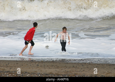 two boys playing in waves at seaside. Stock Photo