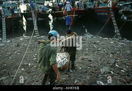 Fishermen carrying a basket of fish at Hong Gai fish market in Halong Bay in Vietnam Stock Photo