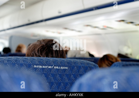 Interior of airliner showing seat backs and Fasten Seat Belt While Seated message Stock Photo