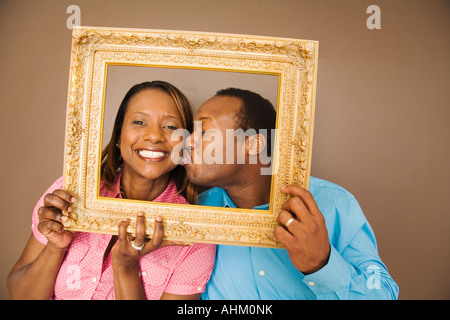 African man kissing wife in picture frame Stock Photo