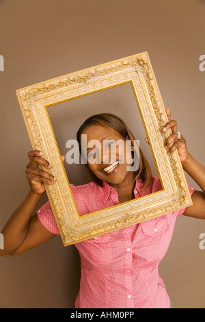 African woman looking through picture frame Stock Photo