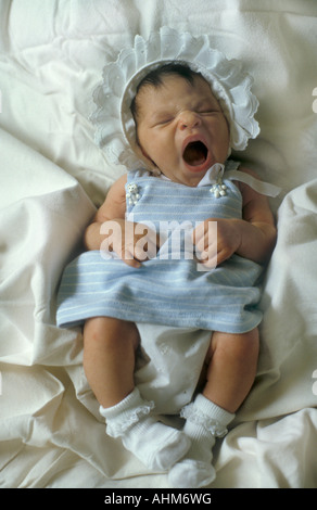 cute little baby in frilly hat yawning Stock Photo