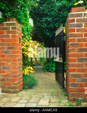 Block laid garden path leading through iron gate into garden Stock Photo
