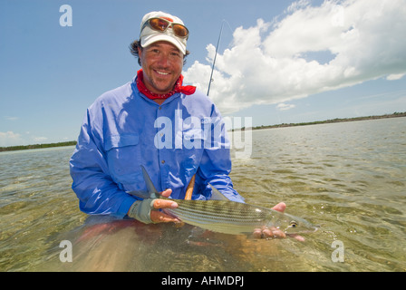 Florida Key Happy  fisherman landing and releasing a bonefish while fly-fishing the flats of the Caribbean ocean Stock Photo