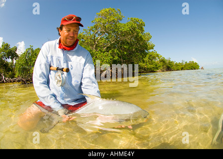 Florida Key Happy Fisherman releasing large Permit in the flats and mangroves of the Caribbean Ocean Stock Photo