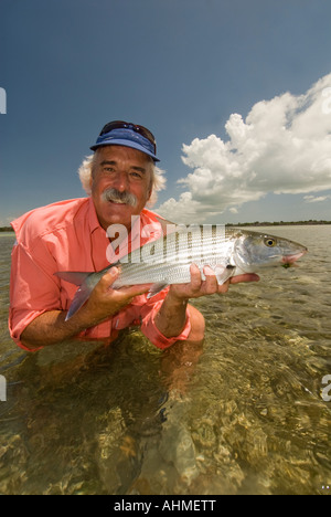 Florida Keys Smiling mature fisherman releasing a bonefish caught while fly-fishing the flats of Caribbean ocean Stock Photo