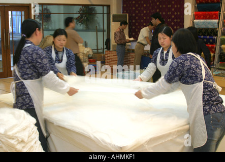 Female workers stretching sheets of silk in a factory showroom in Shanghai,China. Stock Photo