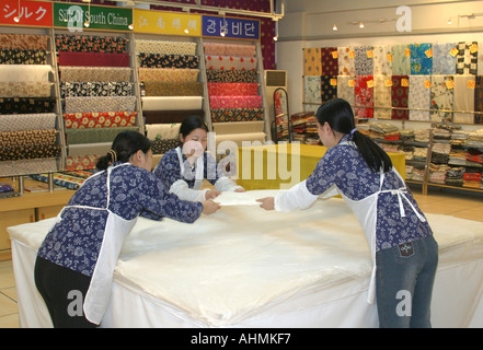 Female workers stretching sheets of silk in a factory showroom in Shanghai,China. Stock Photo