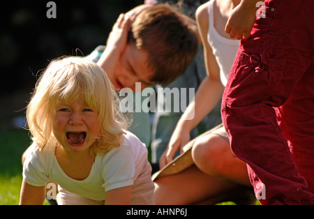 Children playing in garden and a girl crying Stock Photo