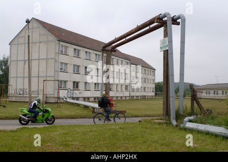 Socialist era poor housing with utility pipes crossing a road in the former East German town of Greifswald Stock Photo