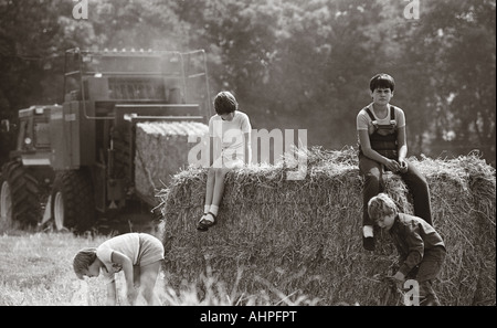 Group of children playing on straw bales immediately after harvest. Stock Photo