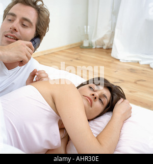 Couple in bed woken by phone Stock Photo