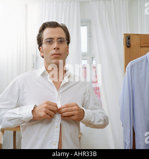 Man buttoning up shirt Stock Photo