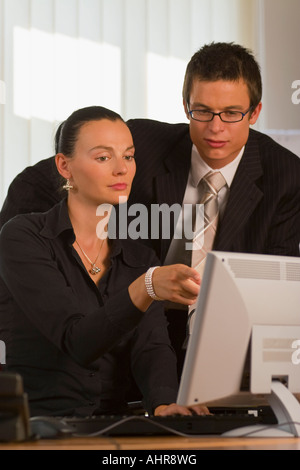 A male and female office worker looking together at a computer monitor Stock Photo