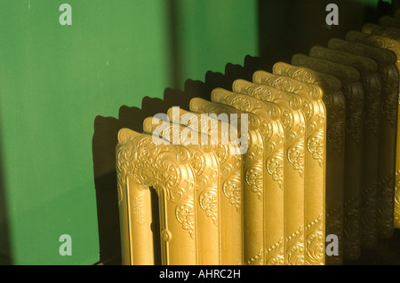 Gold colored radiator and green wall Stock Photo