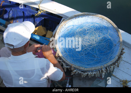 Fisherman baiting fish hooks, Saranda Marina, Saranda, Vlorë County, Albania Stock Photo