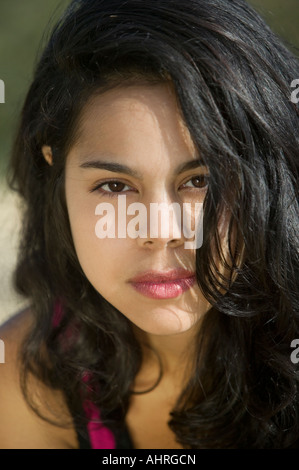 Hispanic woman with tousled dark hair standing indoors looking aside