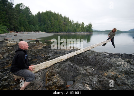 2 kayakers have fun on a drift log teeter totter Vargas Island BC Stock Photo