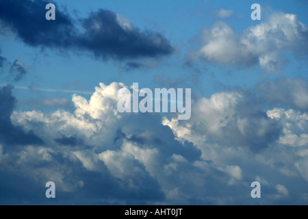 Blue sky filled with fluffy white and dark clouds, creating a dramatic and serene atmosphere in a natural outdoor setting. Stock Photo