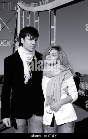 Young man and a woman walking together across the bridge Stock Photo