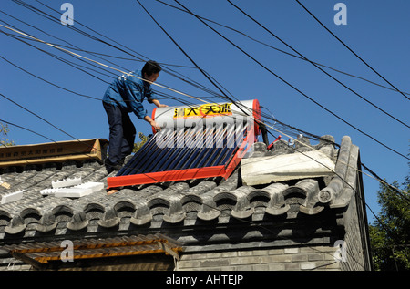 A man installs Solar power powered hot water heater tank on house roof in central Beijing , China. 14 Oct 2007 Stock Photo