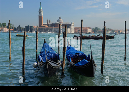 Docked Gondolas and passing boats on Giudecca Canal with San Giorgio Maggiore Island church Venice Italy Stock Photo