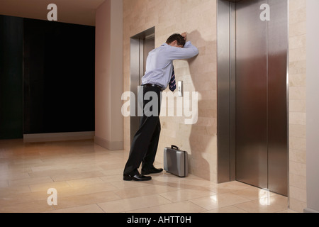 Man with his head down leaning against wall Stock Photo