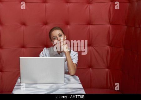 Businesswoman working at a table with red seating Stock Photo