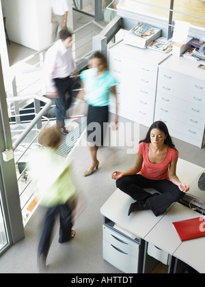 Young woman in a yoga position sitting on her work desk Stock Photo